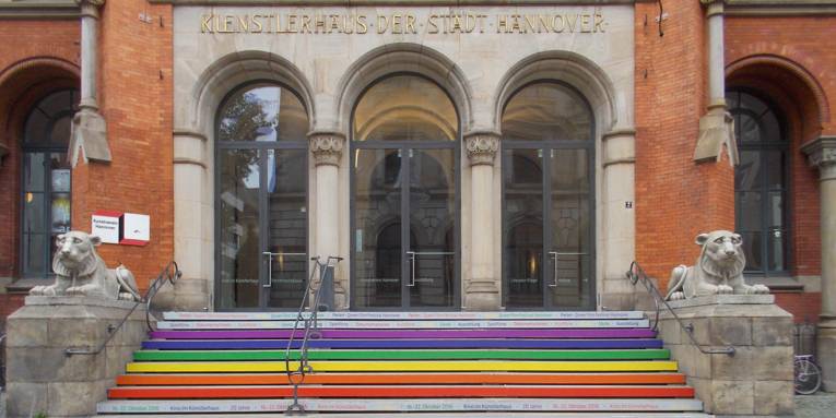 Auf dem Foto sieht man den Eingang des Künstlerhauses Hannover. Die Treppenstufen sind mit Folien in Regenbogenfarben beklebt.